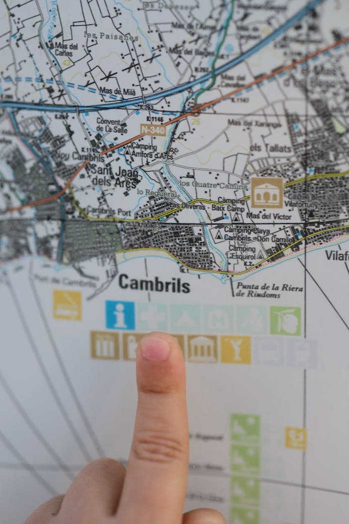 Map of Cambrils with a finger pointing at the location, highlighting travel information.